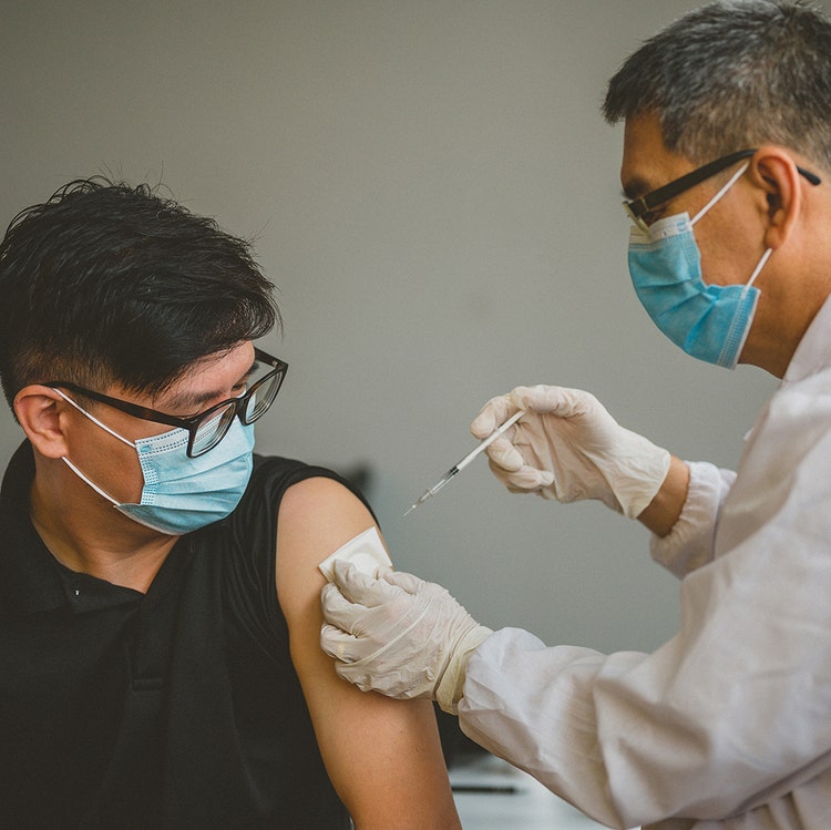An Asian doctor working with patient&#39;s arm. Physician giving vaccination and immunity to virus with syringe. Vaccine and syringe injection It use for prevention, immunization and treatment from COVID-19.