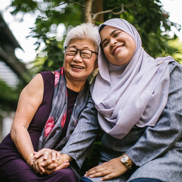 Senior Chinese woman and adult Malaysian woman wearing hijab,having fun outdoors