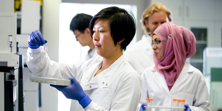 An Asian female scientist places samples, ready to run tests in a state of the art lab.